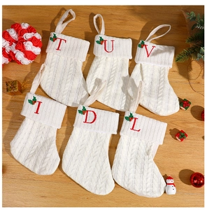 Macro shot of white knitted Christmas stockings with red embroidered letters on wood