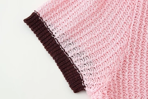 Detail of pink knitted fabric with dark brown ribbed hem texture and stitching