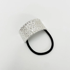 Close-up of silver irregular textured metal detail on elastic hair tie for women