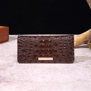 Detail showing deep brown crocodile embossed leather texture with a gold metal clasp