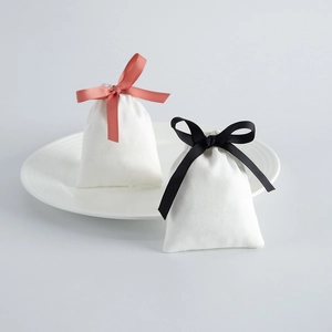 Close-up of white velvet drawstring jewelry pouches with pink and black ribbon bows