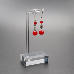 Pair of bright red beaded earrings with metal flowers on a clear acrylic jewelry display
