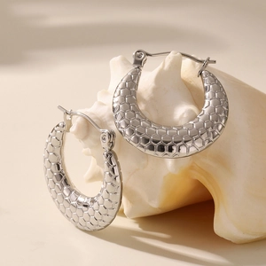 Silver geometric U-shaped hoop earrings with honeycomb texture displayed on a sea shell