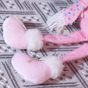 Dettaglio dei piedi a cuore in velluto rosa e gambe lunghe con paillettes della bambola