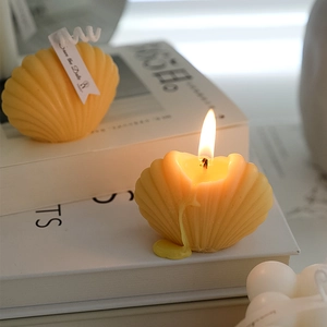 Shell shaped scented candle in yellow wax placed on decorative books for wedding gift