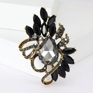 Macro shot of vintage crystal brooch featuring a large pear-shaped grey stone and black gems