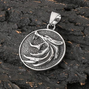 Detail of Viking wolf moon pendant in stainless steel on dark textured rock
