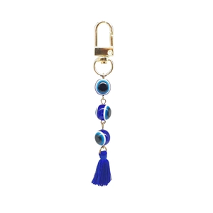 Detail view of gold-plated evil eye keychain with blue beads and matching tassel