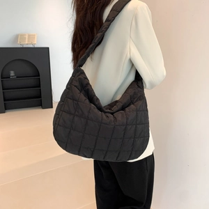 Fashionable black quilted tote bag in space cotton worn by a model in a white blazer