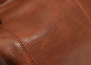 Close-up of brown litchi pattern leather with refined stitching on a large tote bag