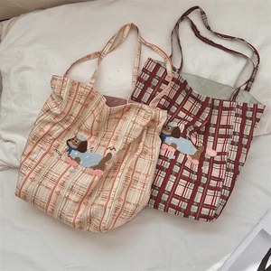 Detail of checkered canvas tote bags with cute dog embroidery and nice text in beige and red