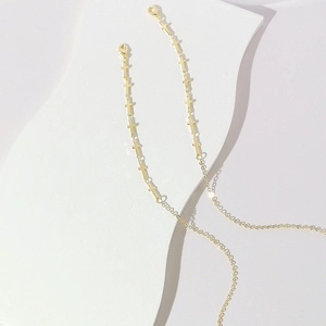 Detail of gold-plated eyeglass chain featuring cross charms and lobster clasps