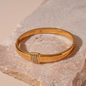 Detail view of gold metal bangle with pavé-set crystals on stone display stand