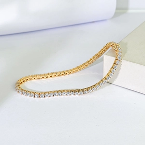 Macro shot of gold tennis bracelet with brilliant round-cut white zircons on white pedestal
