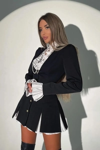 Detail of black two-piece set with white ruffles and silver buttons on the blazer