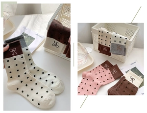 Detailed macro view of polka dot crew socks featuring delicate bow embroidery and color blocking
