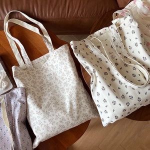 Close-up of floral print cotton canvas tote bags featuring double handles on a wooden table