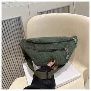 Detail of green corduroy waist bag with dual zippers and adjustable woven strap