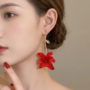 Exaggerated long red flower drop earrings with golden vine hooks on female model