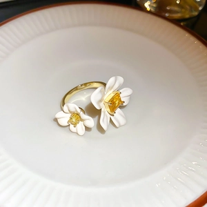 Detailed close-up of gold flower ring with white enamel petals and yellow zircon stones