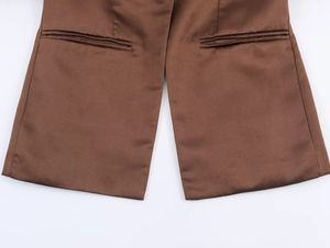 Détail des poches à rabat symétriques et texture satinée sur blazer marron