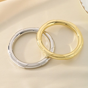 Detail view of gold and silver chunky bangles with quilted texture on beige silk