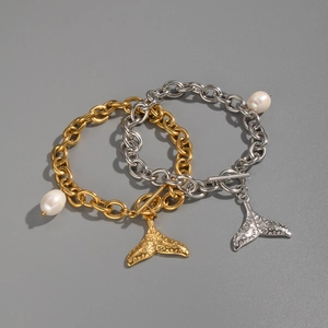 Détail de bracelets à grosse chaîne en or et argent avec perles et breloques queue de poisson