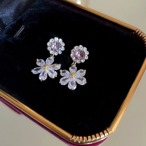 Detailed macro view of purple zircon flower earrings set in a black jewelry gift box