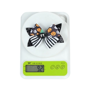 Detailed macro view showing a Halloween spider bow hair clip on a digital scale weighing 9.2g