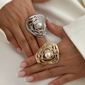Detailed close-up of textured gold and silver pleated rings with faux pearl centers