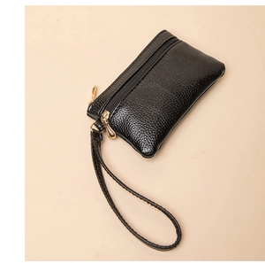 Close-up of black lychee grain leather wallet with gold zipper and wrist strap detail