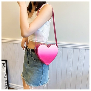 Détail du sac bandoulière en forme de cœur avec dégradé de rose porté par un mannequin