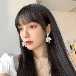 Detailed side view of a model wearing elegant white shell flower earrings with gold studs