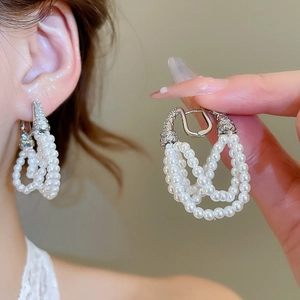 Detailed view of layered pearl tassel earrings with silver finish and zircon accents