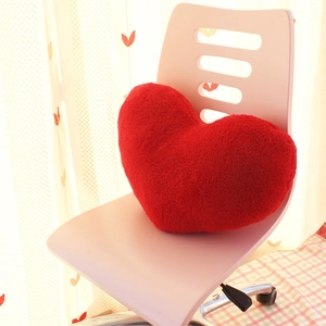 Modern minimalist red heart-shaped plush throw pillow placed on a pink office chair