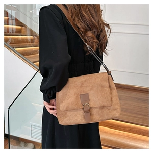 Brown faux suede shoulder bag with adjustable strap shown from a side profile view