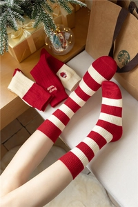 Detailed view of red and white striped Christmas cashmere socks with holiday embroidery