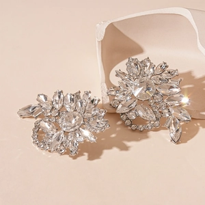 Close-up of geometric flower earrings with silver needles and sparkling crystals