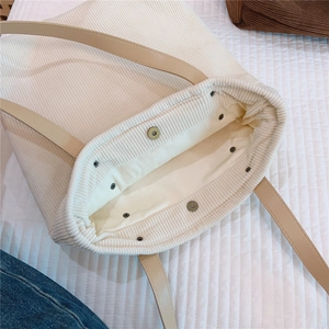 Detail of magnetic snap closure and soft beige corduroy texture on tote bag