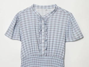 Detail of blue and white plaid dress featuring ruffled neckline and elastic waist texture