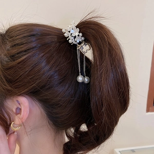Detailed macro of flower hair claw with white pearls and long hanging silver chain tassels