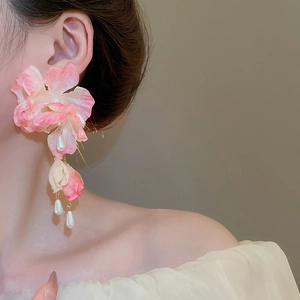 Detail of pink fabric flower earrings with elegant pearl tassels worn by a model