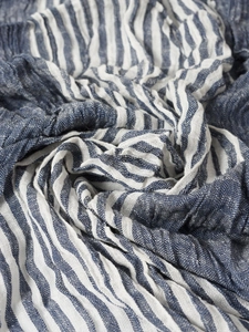 Close-up of blue and white striped scarf fabric showing natural linen texture and wrinkles