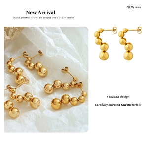 Detailed view of graduated gold steel bead earrings featuring a glossy polished finish