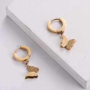 Minimalist gold butterfly earrings with matte finish dangling from round hoop clasps
