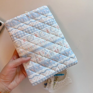 Close-up of blue floral quilted cloth pouch with lace trim and pearl chain strap