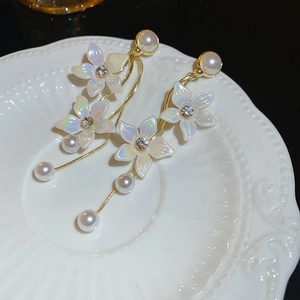 Detailed shot of flower earrings with pearl tassels on a white ceramic display tray