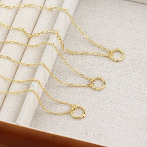 Three gold S925 sterling silver necklaces with paperclip chains and spring clasps on velvet