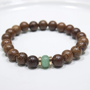 Macro detail of natural wooden beads bracelet with green gemstone and gold metal spacers