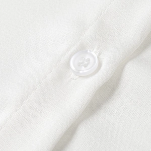 Détail macro de la texture du tissu tissé blanc et du bouton blanc sur la chemise